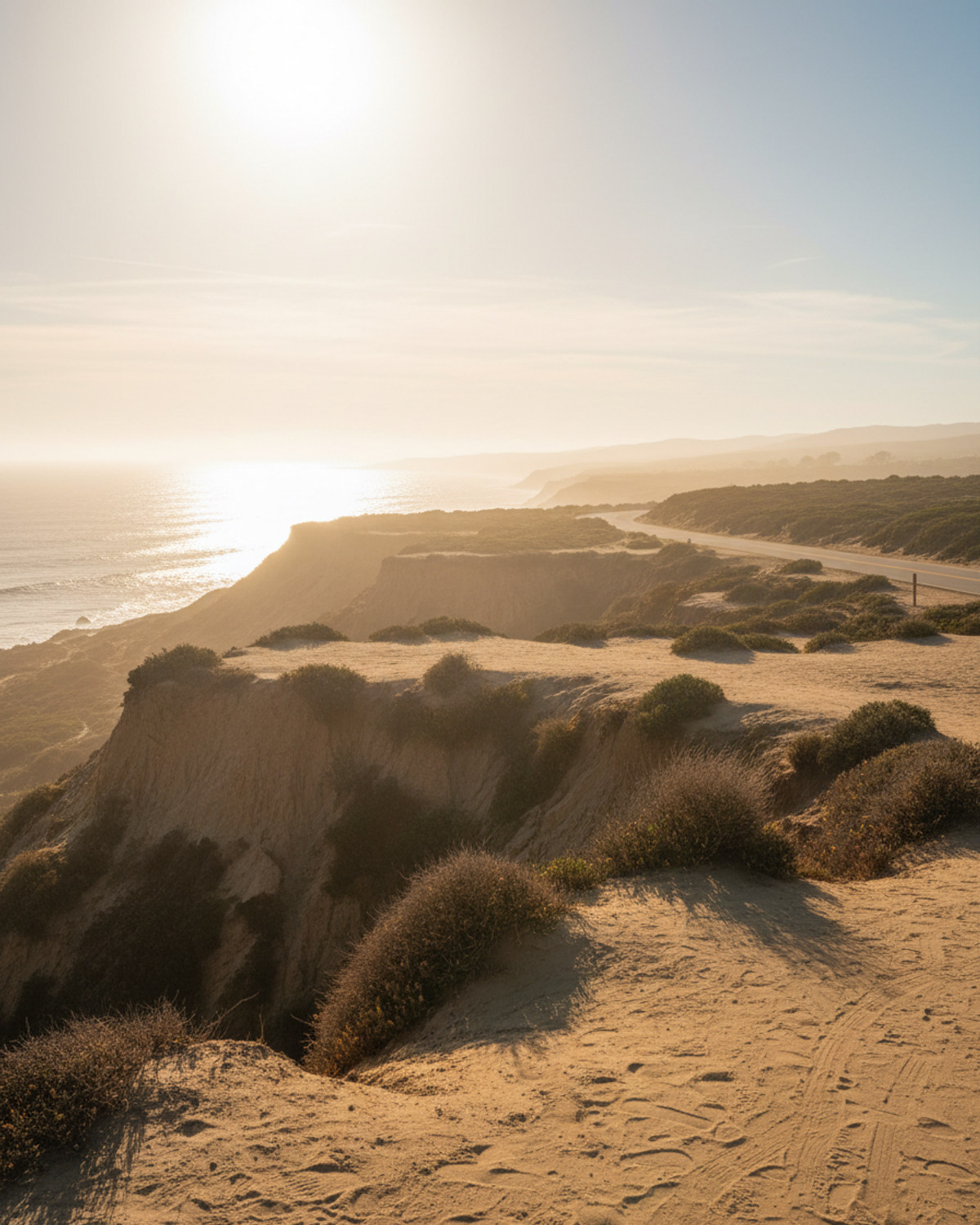 Sun glare cutting through a thin marine layer over a hazy Southern California coastal bluff during a heat wave